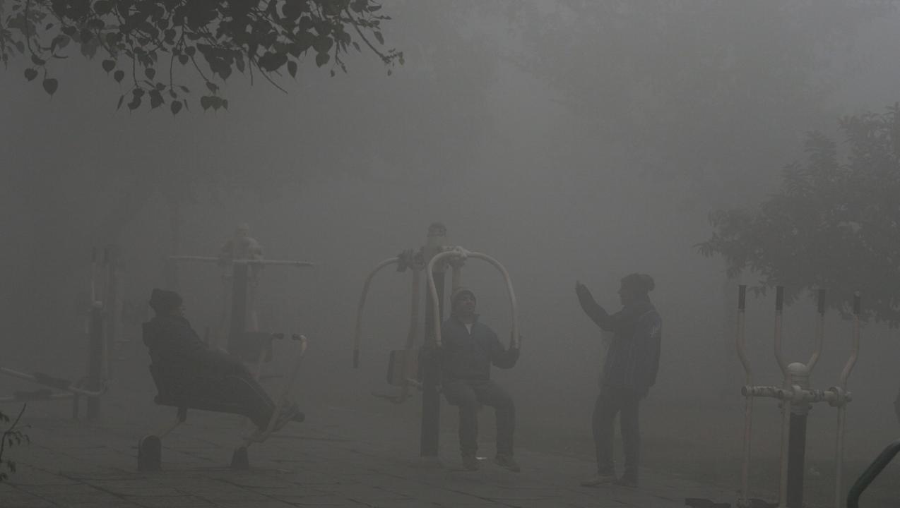 People exercise at an open gym in a park amid low visibility due to a thick layer of fog on a cold winter morning in New Delhi. Pic/PTI